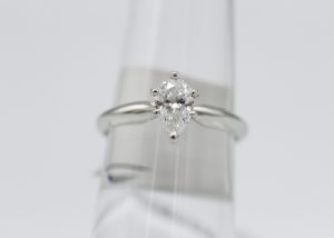 A small silver ring with a large diamond stone centerpiece