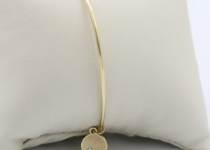 A thin, gold bracelet with pendent