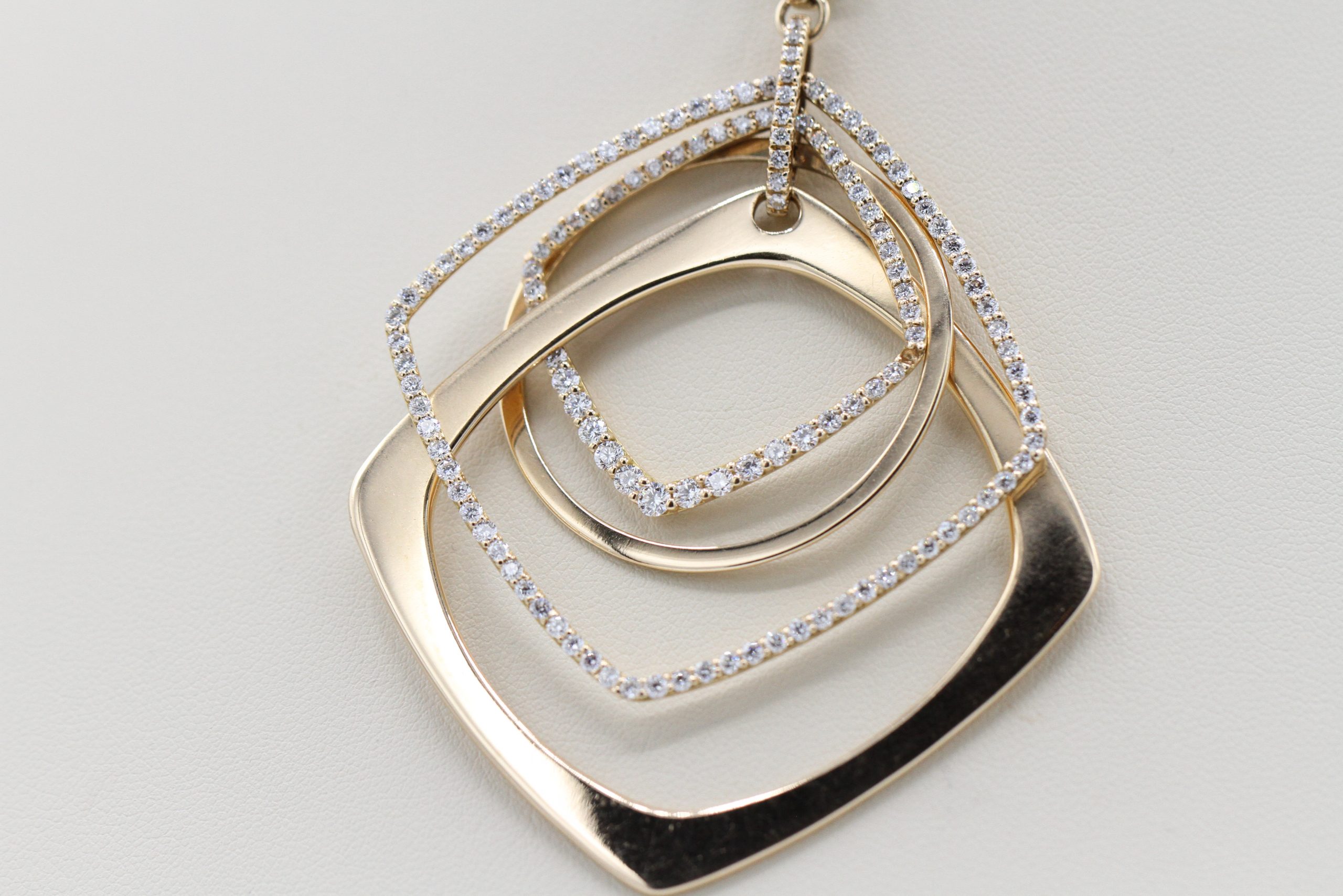 A necklace with a gold, square centerpiece inlaid with diamonds.