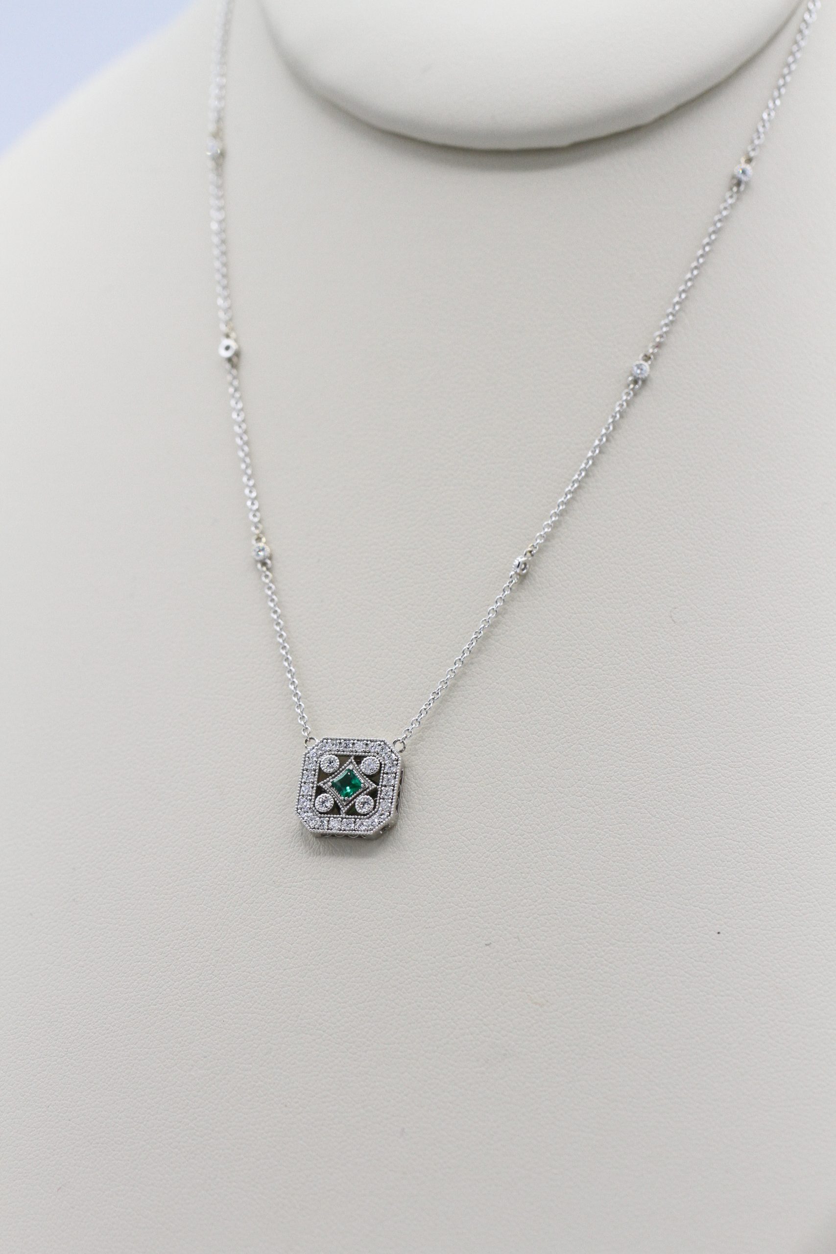 A silver necklace with an emerald centerpiece