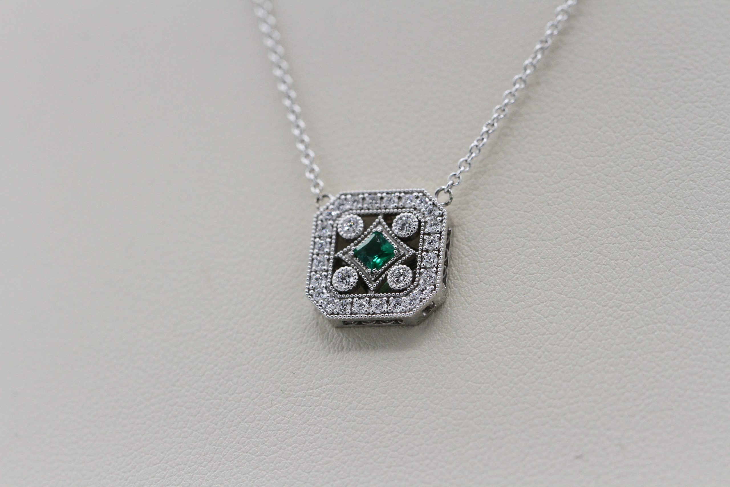 A silver necklace with an emerald centerpiece